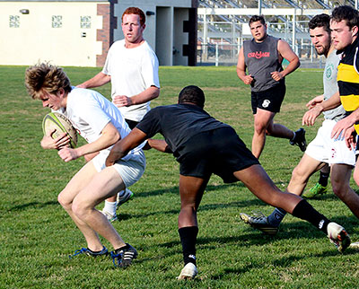 Coaches and players from Chico State tackling each other while playing rugby