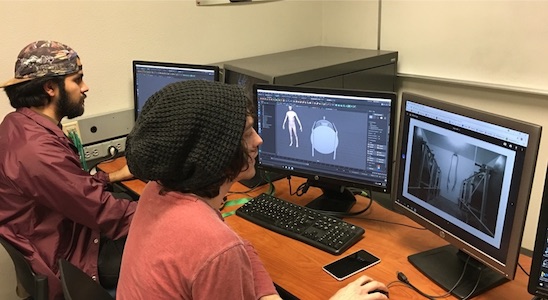 Xavier Burgueno and Jordan Chapin sitting behind computers working on 3D models for the virtual reality project.